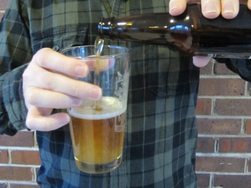 Man pouring beer into pint glass.