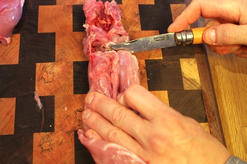 Man cutting off the back legs with knife. 