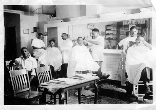 Barber cutting off the client's hair in his shop.