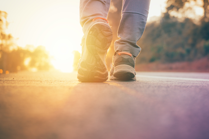 A person walking on a road at sunset, following the rules.